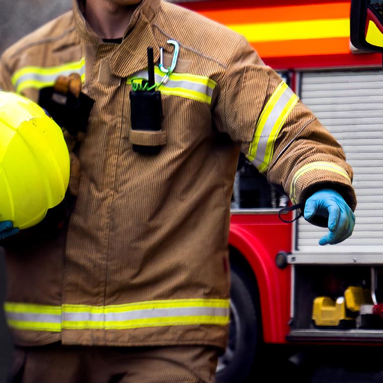 Firefighter in action with hand reaching for fire truck door. An